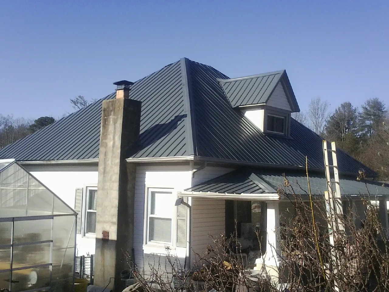 Dark blue standing seam metal roof on a white farmhouse with dormer — Slate & Tile Roof Repair by Roofing Brothers in West Monroe