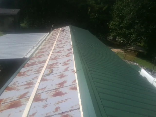 Old rusted panels beside newly installed green metal roofing — Wind Damage Roof Repair by Roofing Brothers in West Monroe