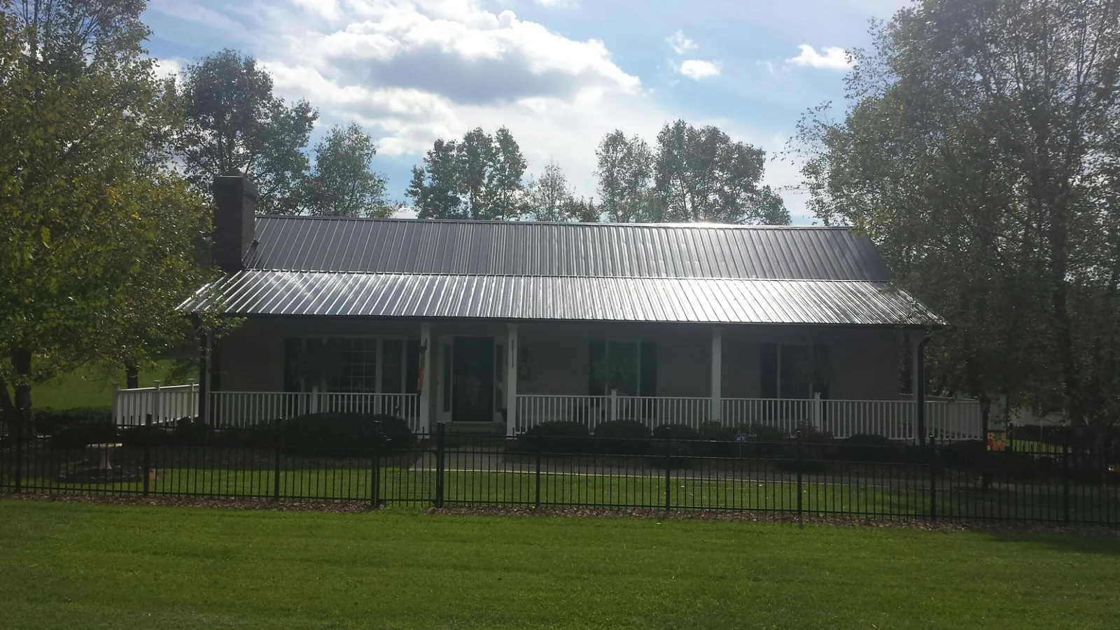 Gray metal roof on a brick ranch with a full width front porch — Gutter Guard Installation work by our crew in West Monroe