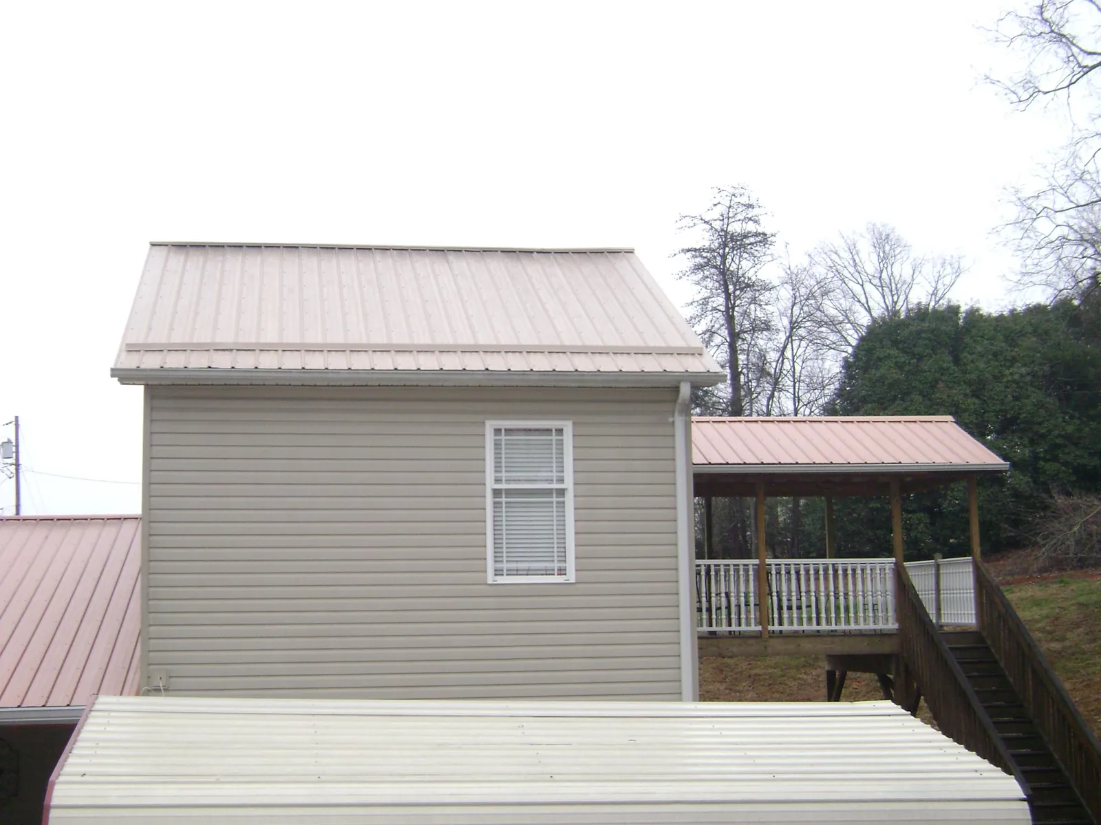 Tan metal roofs on a two story addition and attached porch, from a Roof Replacement job in West Monroe