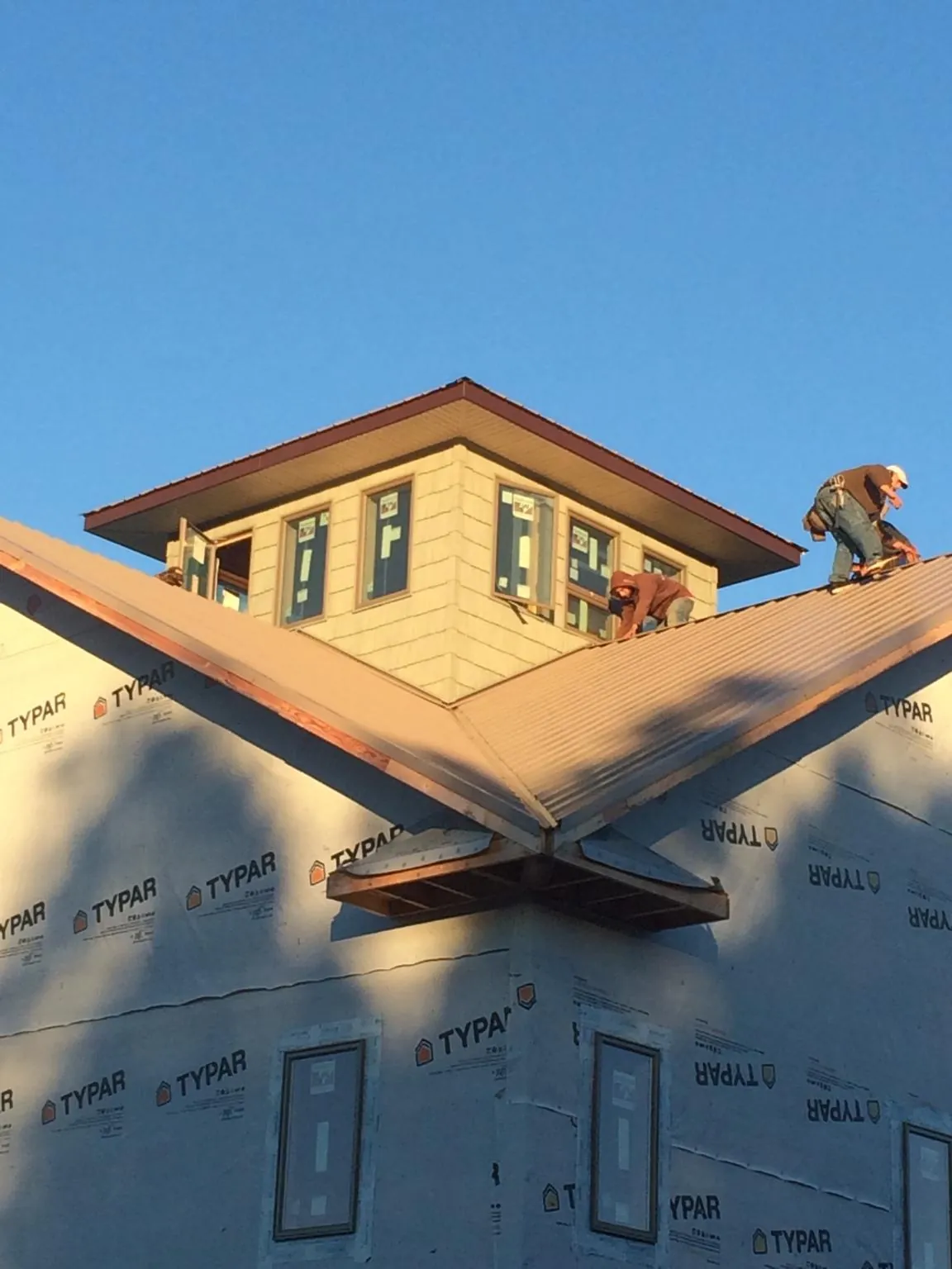 Roofers working around a rooftop cupola on a new metal roof at sunset — Roof Waterproofing in West Monroe by Roofing Brothers